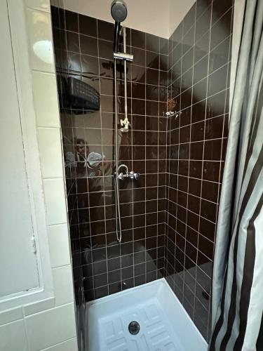 La salle de bains est pourvue d'une douche avec du carrelage noir. dans l'établissement Calm and Comfortable parisian studio, à Paris