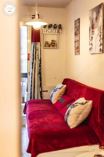 - un canapé rouge avec des oreillers dans le salon dans l'établissement Superdevoluy Appart Rez de Neige, à Saint-Étienne-en-Dévoluy