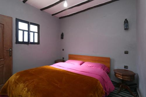 a bedroom with a large bed with pink sheets at Gite Ogog Tacheddirt in Tacheddirt