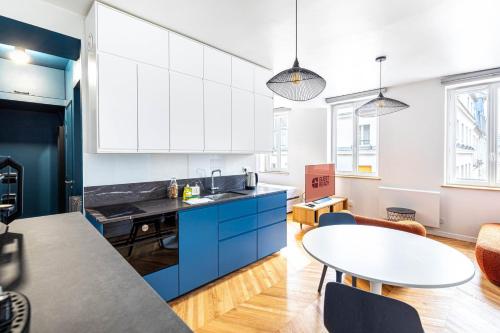 une cuisine avec des armoires bleues et une table dans l'établissement Guestready - Tastefully decorated studio for 2, à Paris
