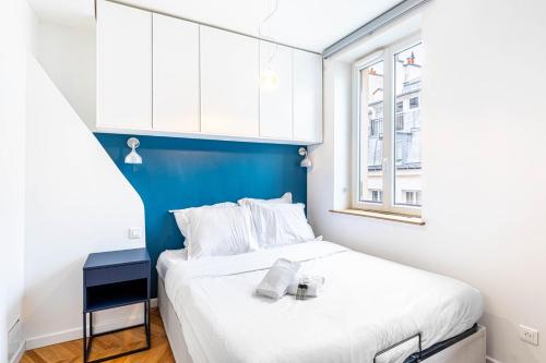 - une petite chambre avec un lit et un mur bleu dans l'établissement Guestready - Tastefully decorated studio for 2, à Paris