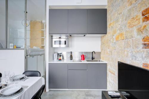 une cuisine avec des placards gris et un mur en briques dans l'établissement Bluestay 150 - Charmant appartement à Paris, à Paris