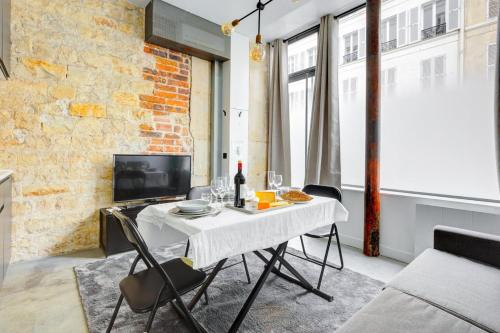 une salle à manger avec une table et des chaises blanches dans l'établissement Bluestay 150 - Charmant appartement à Paris, à Paris