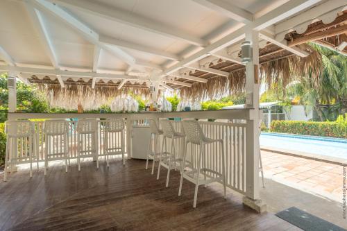 a bar with chairs on a porch with a swimming pool at Domaine de l'Anse Simon - Piscine - 8 chambres in Le Vauclin