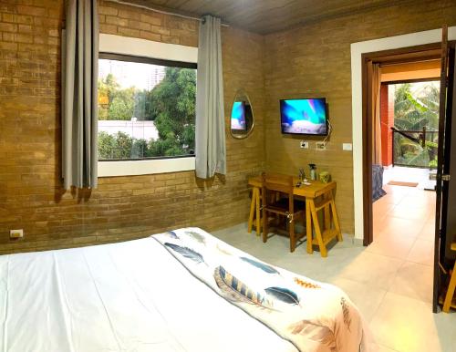 a bedroom with a bed and a table and a television at Jacarecica Haus in Maceió