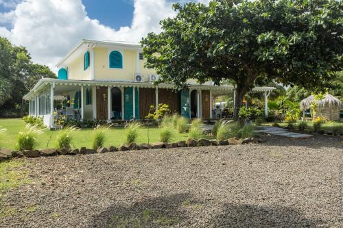 a white house with a tree in the yard at Domaine de l'Anse Simon - Piscine - 8 chambres in Le Vauclin