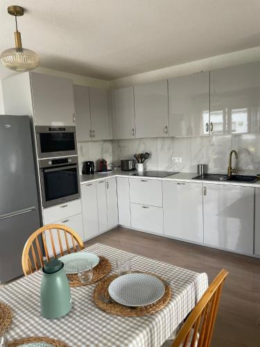 une cuisine avec des placards blancs et une table avec des assiettes. dans l'établissement Appartement 3 chambres, Terrasse, Parking, Clim', à Bordeaux