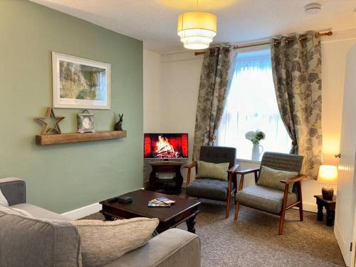 a living room with a couch and chairs and a fireplace at Miners Cottage in Snowdonia in Blaenau-Ffestiniog