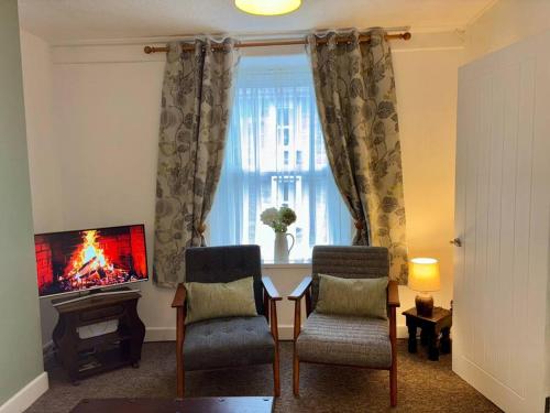 a living room with a table and two chairs and a television at Miners Cottage in Snowdonia in Blaenau-Ffestiniog