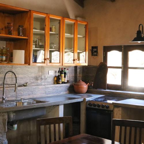 a kitchen with wooden cabinets and a sink and a stove at Hostal SPA Casa de Piedra in La Quebrada