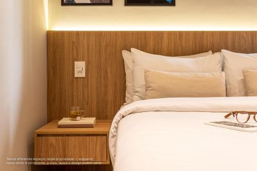 a bedroom with a bed and a night stand with a glass on it at Next Paulista by Viva - Apartamentos completos ao lado da Av Paulista e MASP in São Paulo