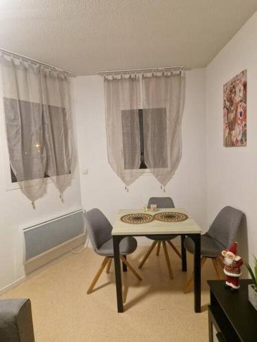 - une salle à manger avec une table, des chaises et des rideaux dans l'établissement Beau T2 proche de Toulouse, à Rouffiac-Tolosan