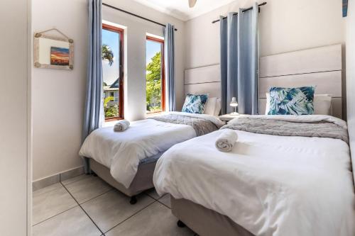 two beds in a room with two windows at The Bridge Unit 8 in St Lucia