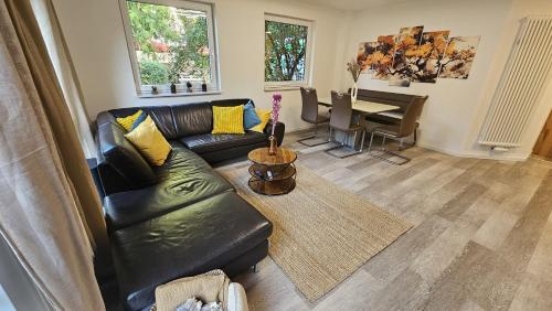 a living room with a black leather couch and a table at Ferienwohnung am Stadtpark 2 Terrassen, 2BR, 84m2 in Ilmenau