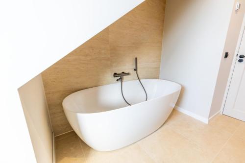 a bath tub in the corner of a bathroom at Casiola - Family stay with Garden & Sauna in Cadzand
