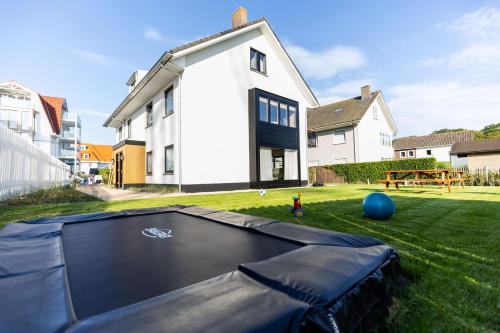 a house with a trampoline in the yard at Casiola - Family stay with Garden & Sauna in Cadzand