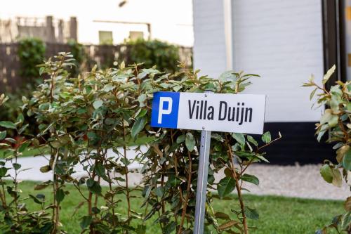 a blue and white parking sign in front of a bush at Casiola - Family stay with Garden & Sauna in Cadzand