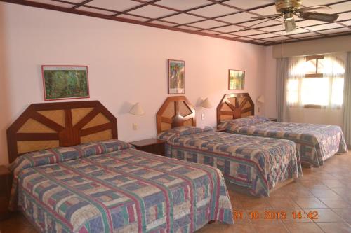 a hotel room with three beds in a room at El Tucano Resort & Thermal Spa in Quesada