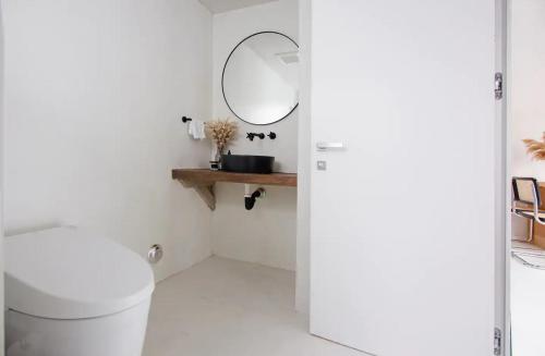 un baño con inodoro y espejo en Atelier Lumi - at lumicollection, en Miami