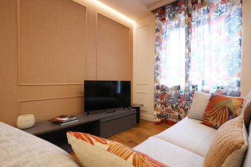 a living room with a couch and a flat screen tv at All'Angolo Deluxe Apartment in Alba