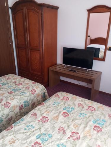 a bedroom with two beds and a tv and a dresser at Regina Hotel Pollino in Morano Calabro
