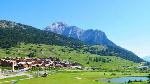 a village in a green field with mountains in the background at Refuge Montagnard à Montgenèvre in Montgenèvre