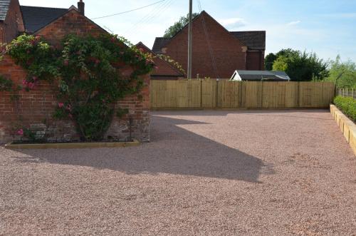 a driveway with a fence and a brick building at The Red Lion, Madley in Hereford