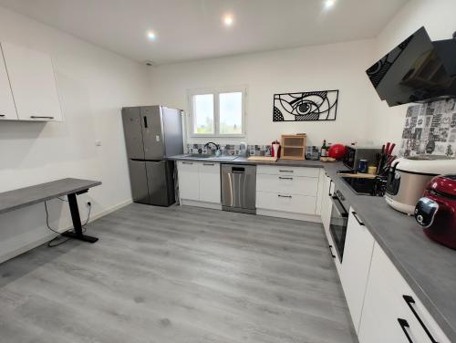 une grande cuisine avec des placards blancs et des appareils en acier inoxydable dans l'établissement Appartement Familial proche de Carcassonne, à Villemoustaussou