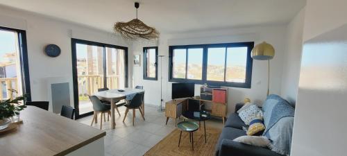 un salon avec un canapé et une table avec des chaises dans l'établissement Le ricochet, à Mimizan-Plage