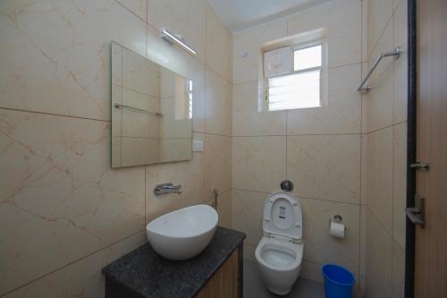 a bathroom with a toilet and a sink and a mirror at Lykke Suites- 2-min Drive to Colva Beach-By Goan Felicidade Hospitality PVT LTD in Colva
