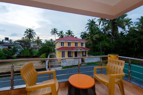 a balcony with two chairs and a table and a house at Lykke Suites- 2-min Drive to Colva Beach-By Goan Felicidade Hospitality PVT LTD in Colva