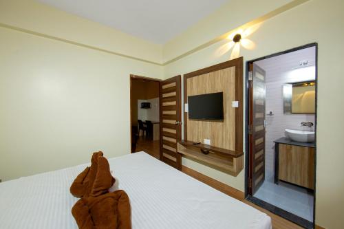 a bedroom with a bed and a bathroom with a sink at Lykke Suites- 2-min Drive to Colva Beach-By Goan Felicidade Hospitality PVT LTD in Colva