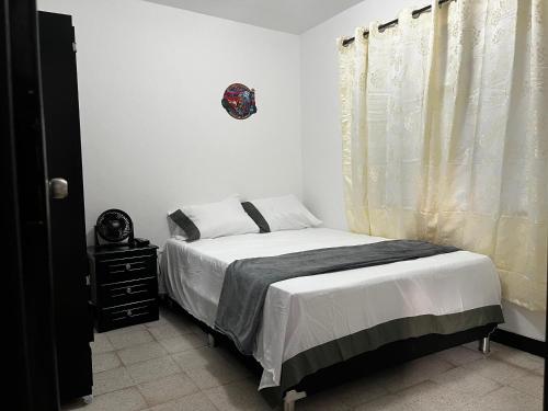 a white bedroom with a bed and a window at Hogar El Descanso Itagui in Itagüí