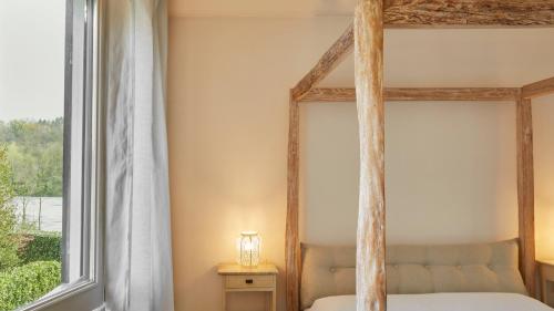 a bedroom with a four poster bed and a window at Il Fiume Azzurro Home B&B in Castelletto sopra Ticino