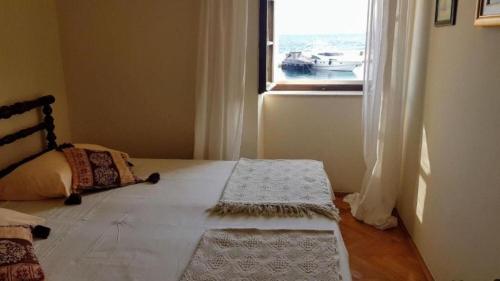 a bedroom with a bed and a window with a boat at Apartments Ela in Sutivan