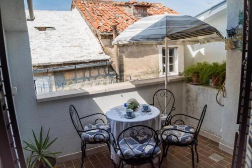 a table and chairs on a balcony with an umbrella at Apartments Ela in Sutivan