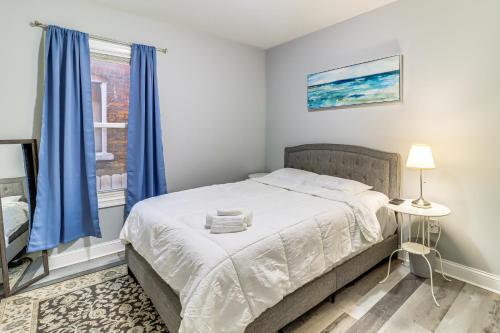 a bedroom with a bed with blue curtains and a window at 4 Mi to Dtwn Detroit Townhome Near North End in Detroit