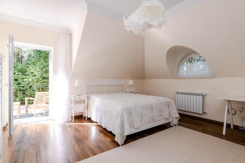 a white bedroom with a bed and a window at Comfortable 4 bedroom villa outdoor wood-fired sauna Warsaw in Magdalenka