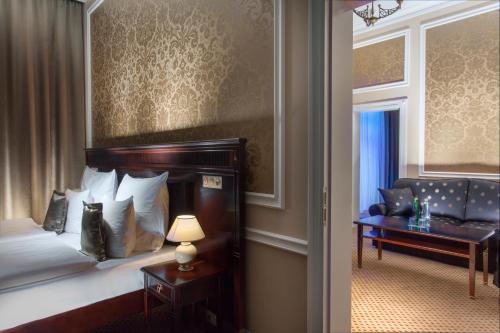 a bedroom with a bed and a couch and a table at Luxury Spa Hotel Olympic Palace in Karlovy Vary