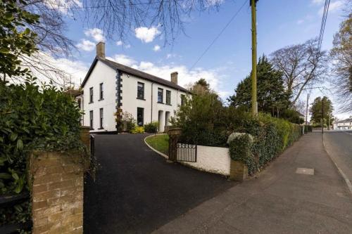 a white house with a fence and a driveway at Bellevue Period House in County Armagh in Bessbrook