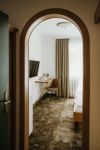 a hotel room with a bed and a desk and a mirror at Pension Baranekhof - closest to the Kitzsteinhorn Ski Resort in Kaprun