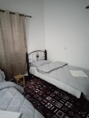 a bedroom with two twin beds and a rug at Hotel AZUL Todra Gorges in Tinerhir