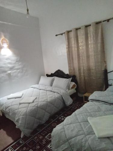 a bedroom with two beds and a window at Hotel AZUL Todra Gorges in Tinerhir