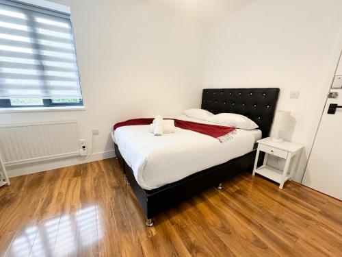 1 dormitorio con 1 cama con cabecero negro y ventana en Centra Palmers Green, en Londres