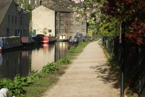 a canal with houses and boats in a city at The Sewing Room in Hebden Bridge