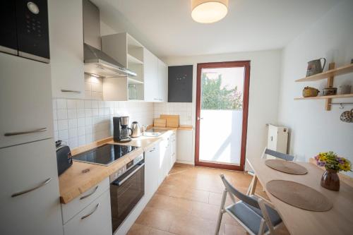 a kitchen with white cabinets and a table with chairs at Haus unterm Mammutbaum - Elberadweg in Magdeburg