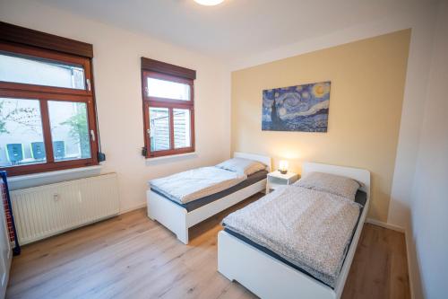 two beds in a room with two windows at Haus unterm Mammutbaum - Elberadweg in Magdeburg