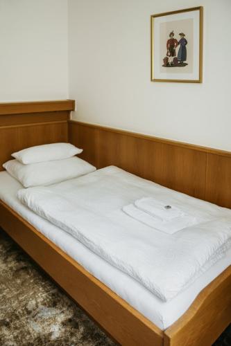 a bed with white sheets and a picture on the wall at Pension Baranekhof - closest to the Kitzsteinhorn Ski Resort in Kaprun