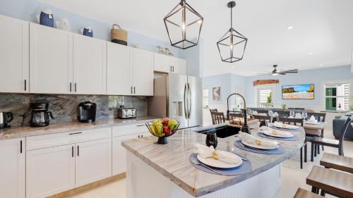 a kitchen with white cabinets and a large island with a table at A Royal Affair by Last Key Realty in Key West