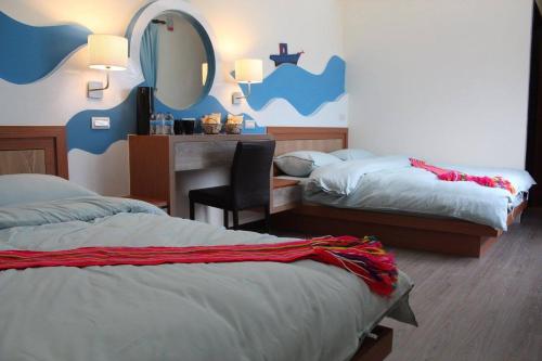 a bedroom with two beds and a desk with a mirror at 巴斯拉岸民宿 in Chenggong